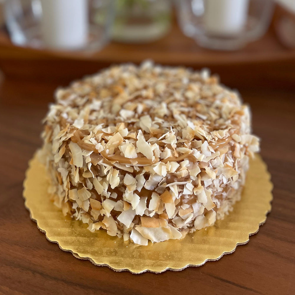 Gluten-free, sugar-free, dairy-free Coconut Full Life Cake topped with sugar-free caramel syrup and golden brown toasted coconut flakes, offering a taste of tropical indulgence.Full Life Gourmet Bakery