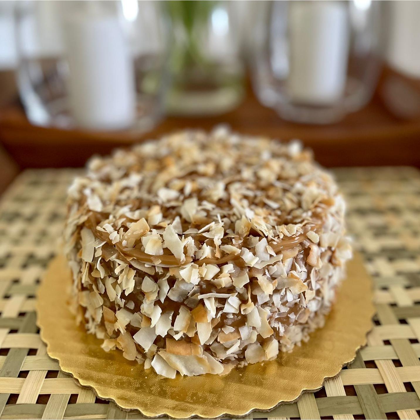Gluten-free, sugar-free, dairy-free Coconut Full Life Cake topped with sugar-free caramel syrup and golden brown toasted coconut flakes, offering a taste of tropical indulgence.Full Life Gourmet Bakery