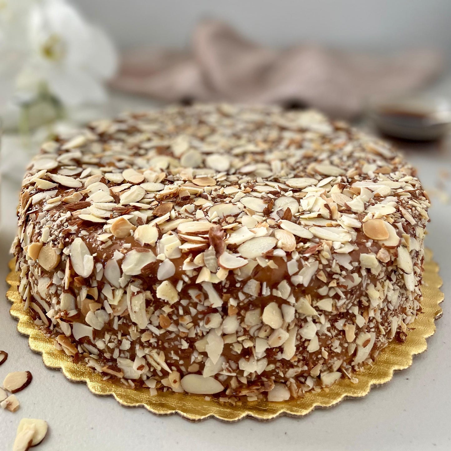 Gluten-free, dairy-free, sugar-free Lemon Lush Cake topped with sugar-free caramel syrup and toasted almonds, highlighting its fluffy texture and zesty lemon flavor. Full Life Gourmet Bakery